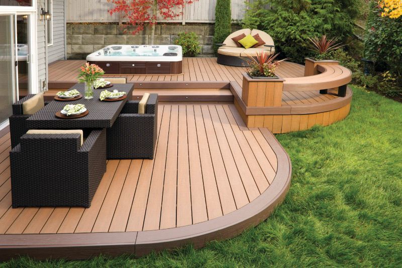 A gray deck with a black roof and trees in the background.