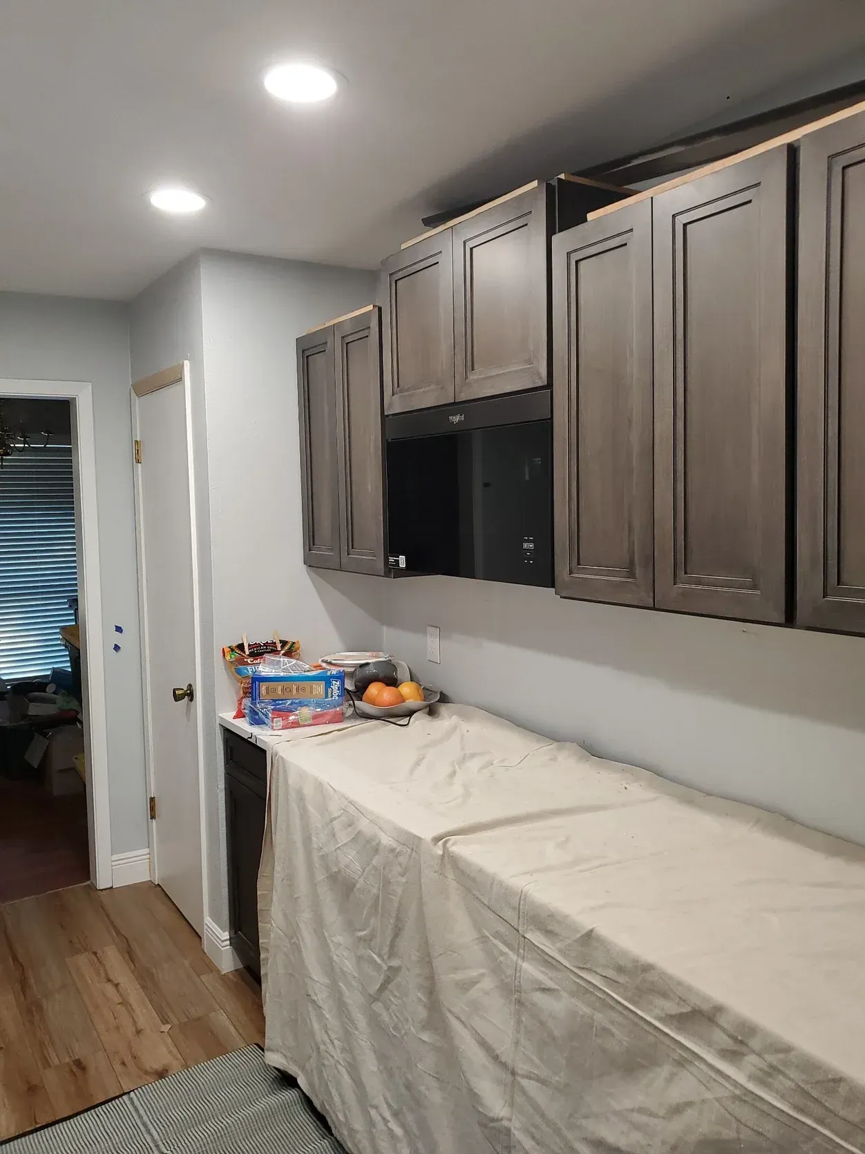 Kitchen with upper cabinets, countertop covered with plastic, and a doorway.