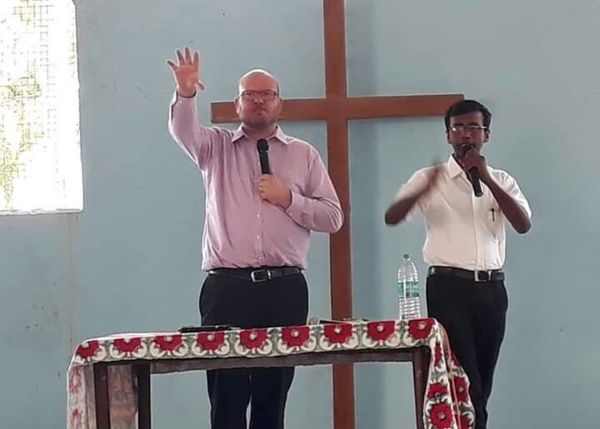two men are standing in front of a cross in a church .