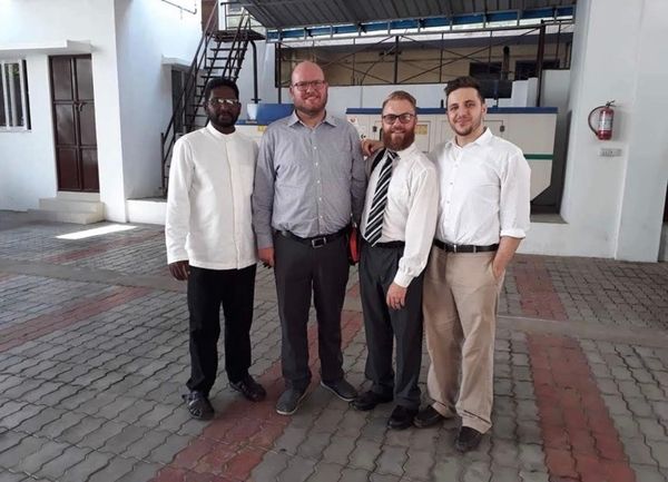 four men are posing for a picture in front of a building