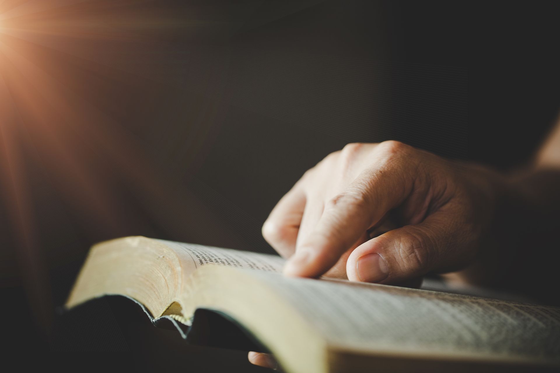 A person is reading a bible in a dark room.