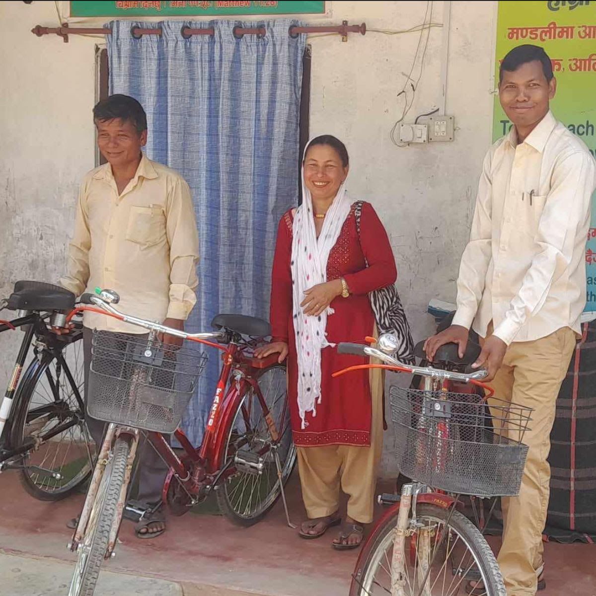 3 happy people standing beside bicycles given to them by World Missions to Asia