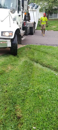 Workers beside white utility truck on a grassy roadside path