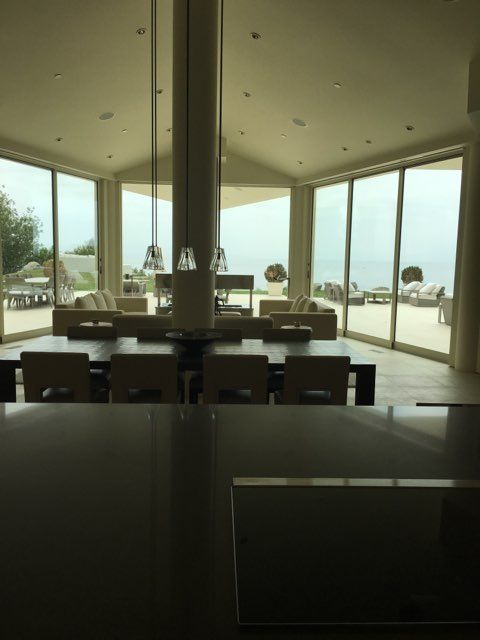 Large modern dining room with expansive windows overlooking a waterfront patio.