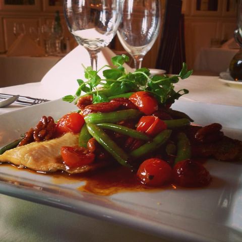 A plate of food with tomatoes and green beans on a table
