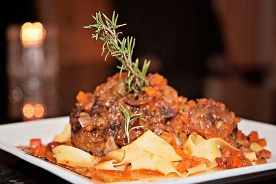 A close up of a plate of food with noodles and meat on a table.