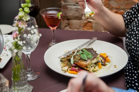 A woman is sitting at a table eating a plate of food.