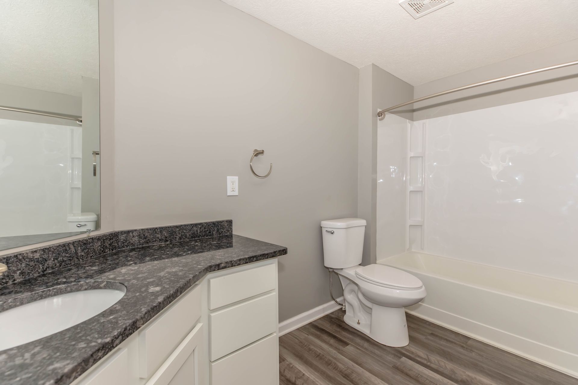 Modern bathroom with gray walls, white vanity, toilet, and bathtub-shower combo at Quarry Apartments for Rent in Columbus, OH.