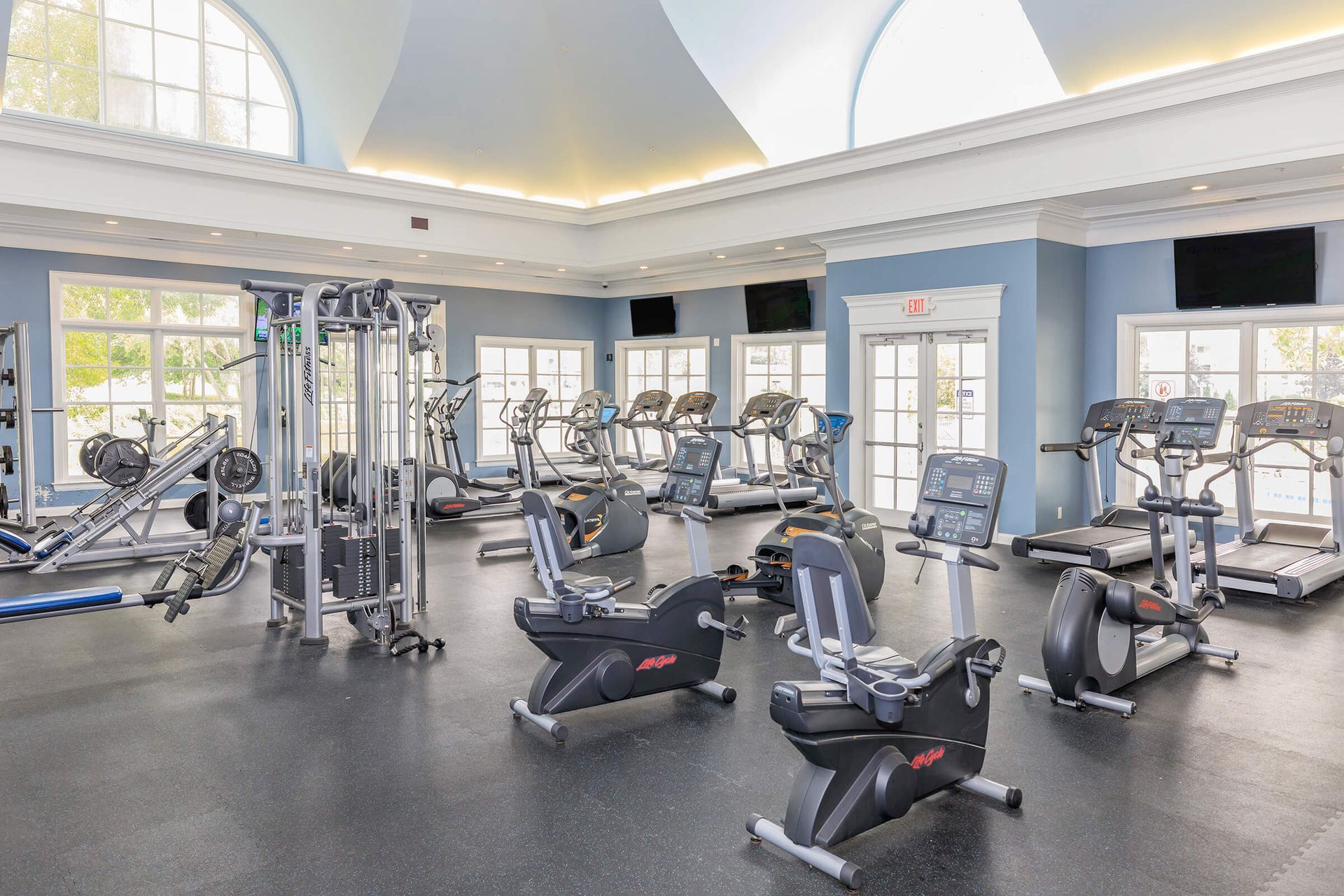 Bright gym with treadmills, exercise bikes, and cable machines in a spacious room with arched windows at Quarry Apartments for Rent in Columbus, OH.