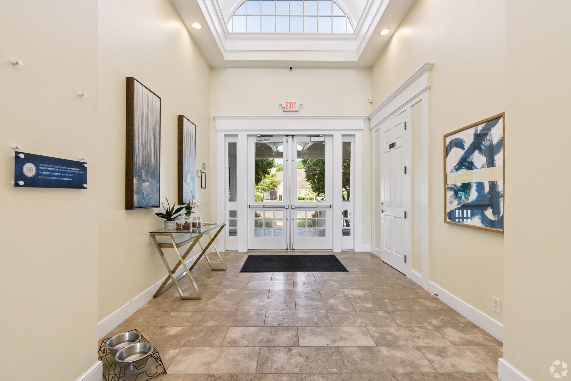 Bright lobby with tiled floor, glass entrance doors, skylight, and framed wall art at Quarry Apartments for Rent in Columbus, OH.
