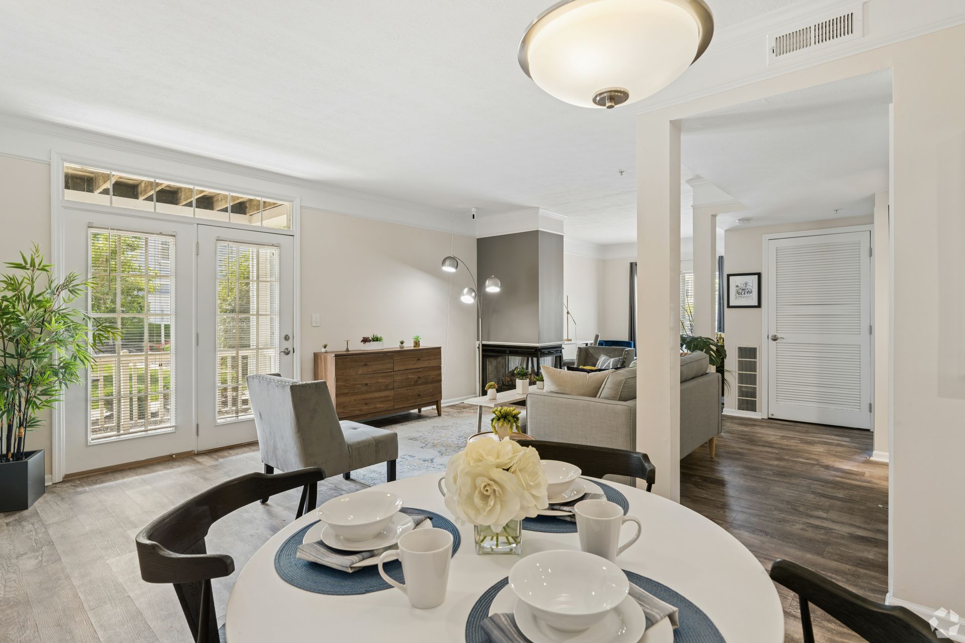 Bright dining and living room with white walls, dark wood floors, and French doors letting in daylight at Quarry Apartments for Rent in Columbus, OH.