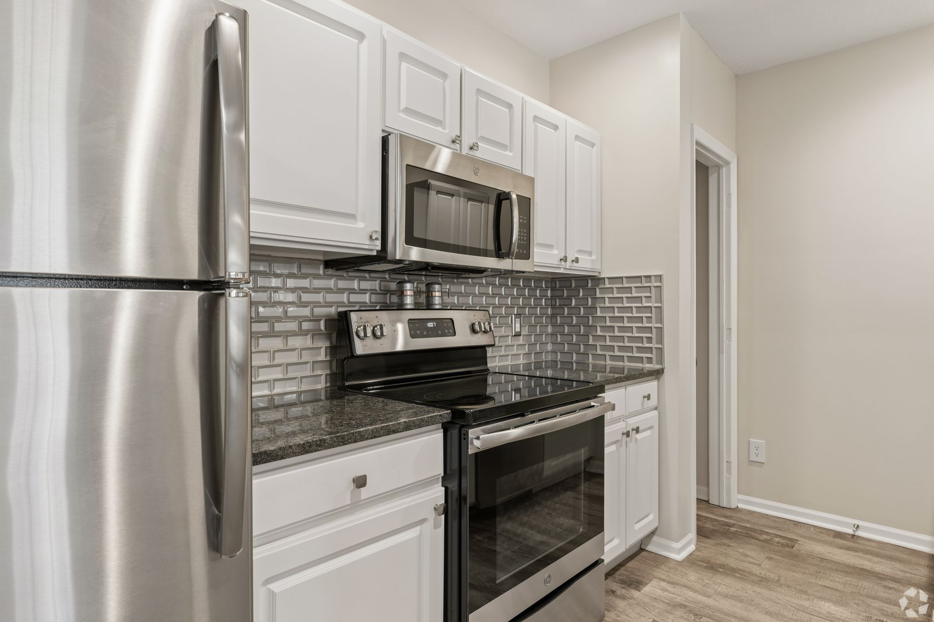 Bright modern kitchen with stainless steel appliances, white cabinets, and gray tile backsplash at Quarry Apartments for Rent in Columbus, OH.