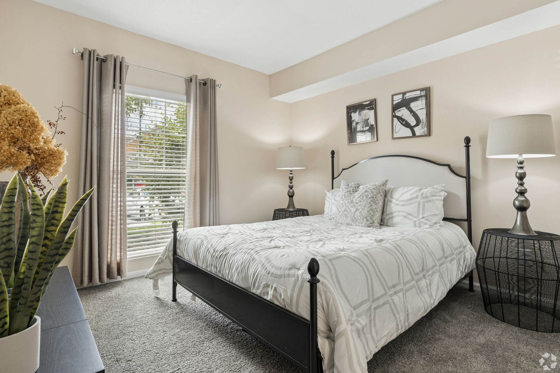 Bright bedroom with a bed, nightstands, lamps, and a window with curtains at Quarry Apartments for Rent in Columbus, OH.