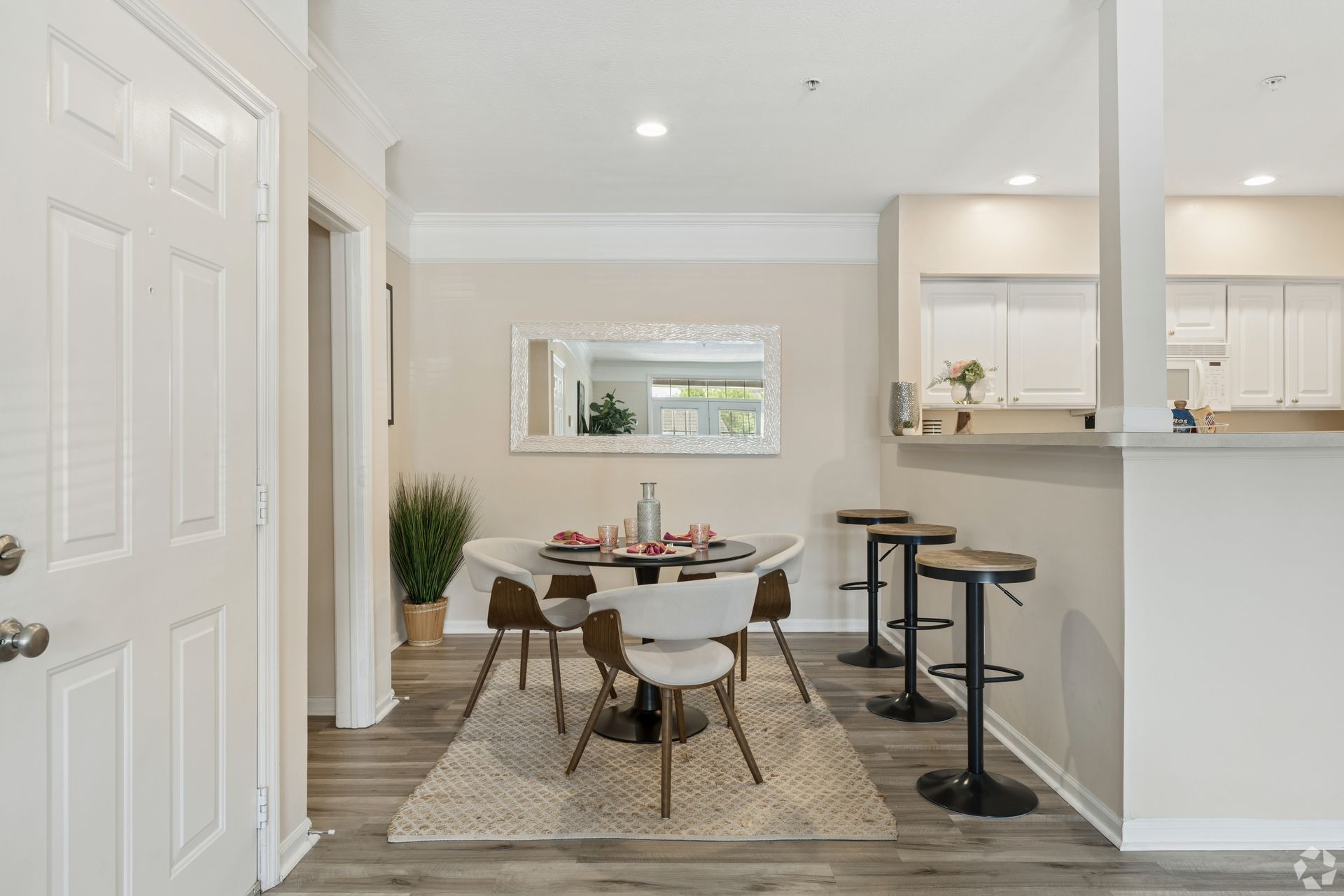 Bright dining area with table, chairs, rug, and kitchen pass-through in a modern home interior at Quarry Apartments for Rent in Columbus, OH.