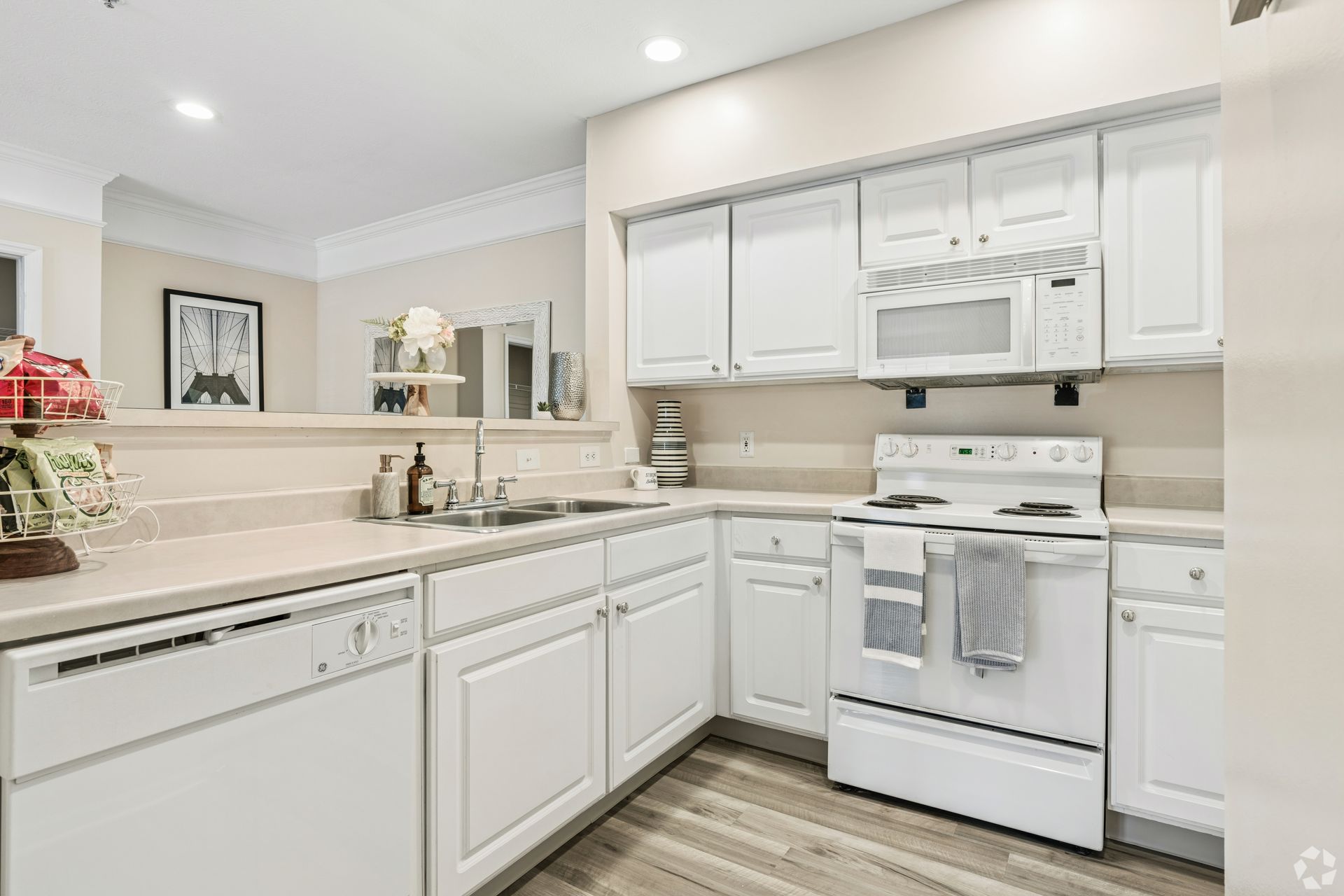 Bright white kitchen with white cabinets, stove, dishwasher, and light countertops at Quarry Apartments for Rent in Columbus, OH.