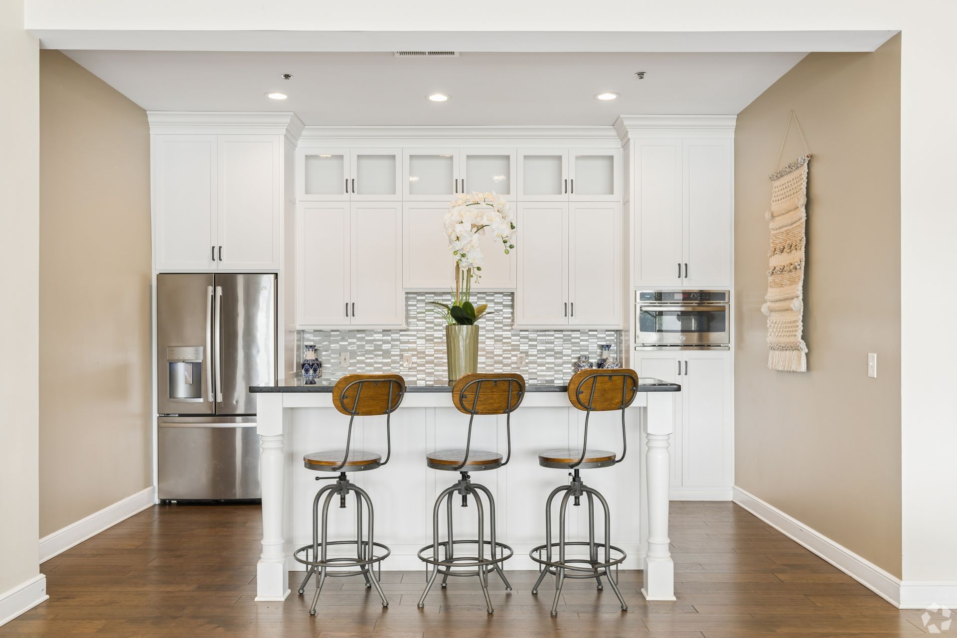 Bright modern kitchen with white cabinets, stainless steel appliances, and a central island with bar stools at Quarry Apartments for Rent in Columbus, OH.