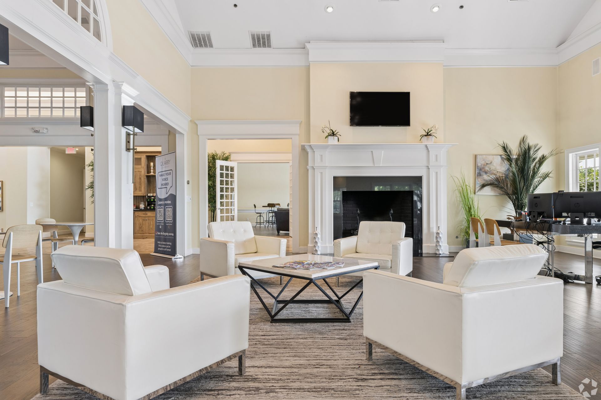 Bright living room with white sofas, fireplace, large windows, and high ceiling at Quarry Apartments for Rent in Columbus, OH.