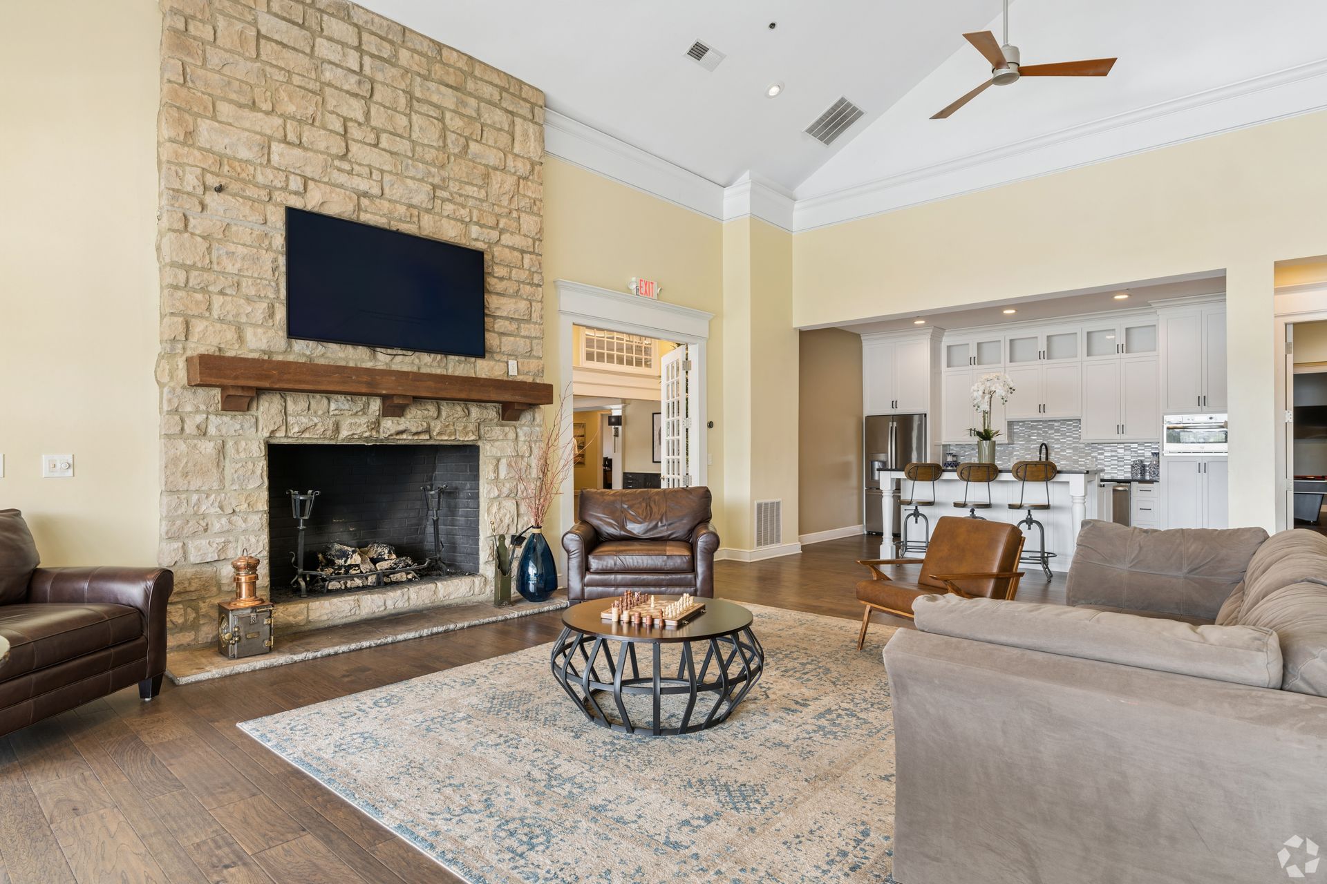 Spacious living room with stone fireplace, TV, sectional sofa, and open kitchen in the background at Quarry Apartments for Rent in Columbus, OH.