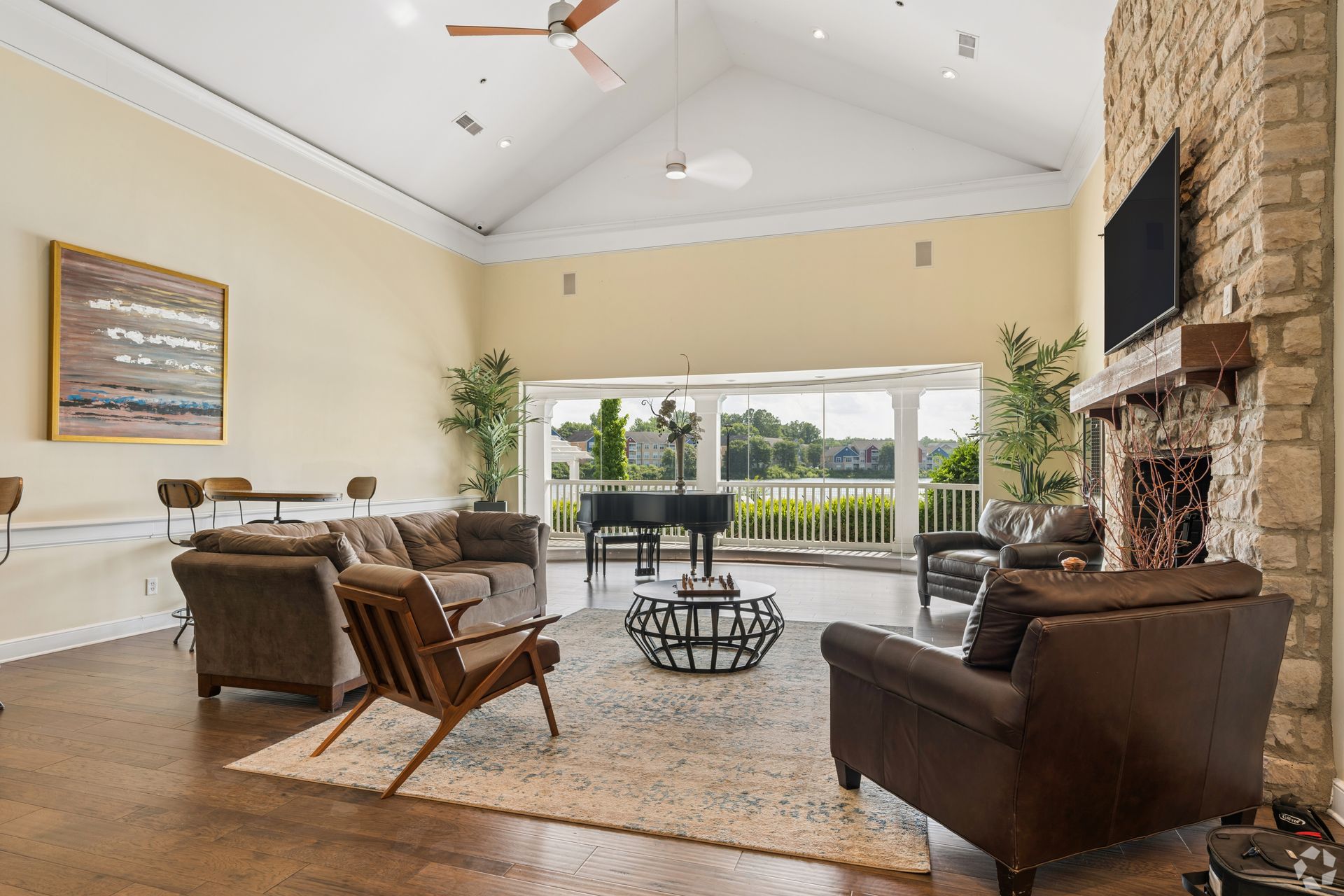 Spacious living room with stone fireplace, leather chairs, and sliding doors opening to a balcony view at Quarry Apartments for Rent in Columbus, OH.
