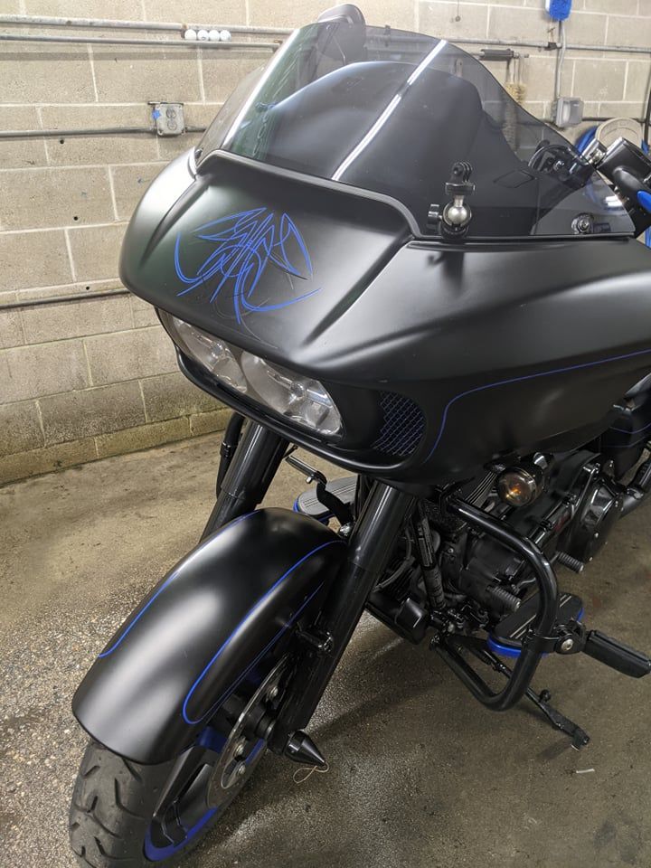 A matte black Harley-Davidson Road Glide motorcycle with blue pinstriping parked indoors on a concrete floor.