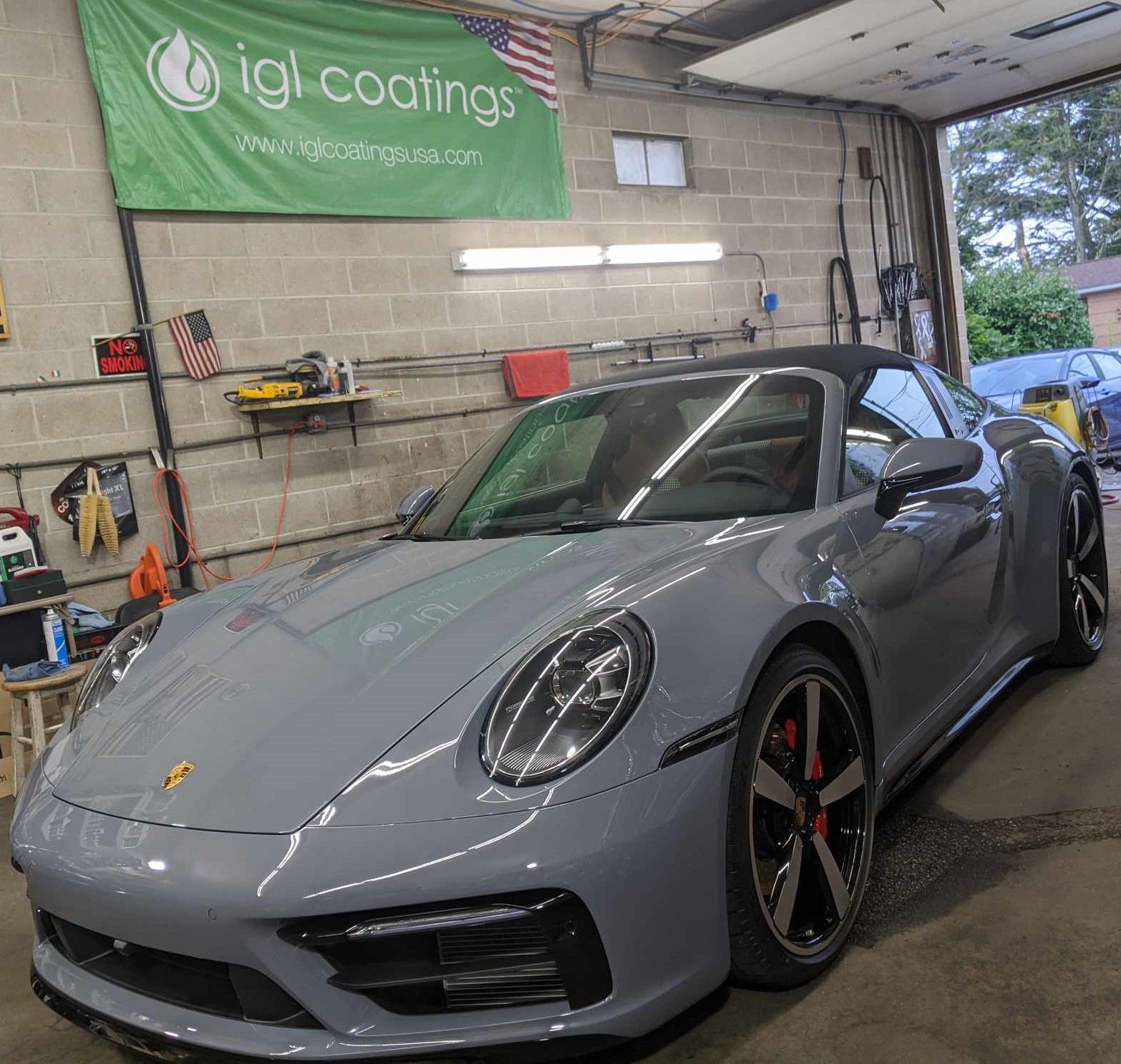 A grey Porsche convertible parked inside an auto shop with an 