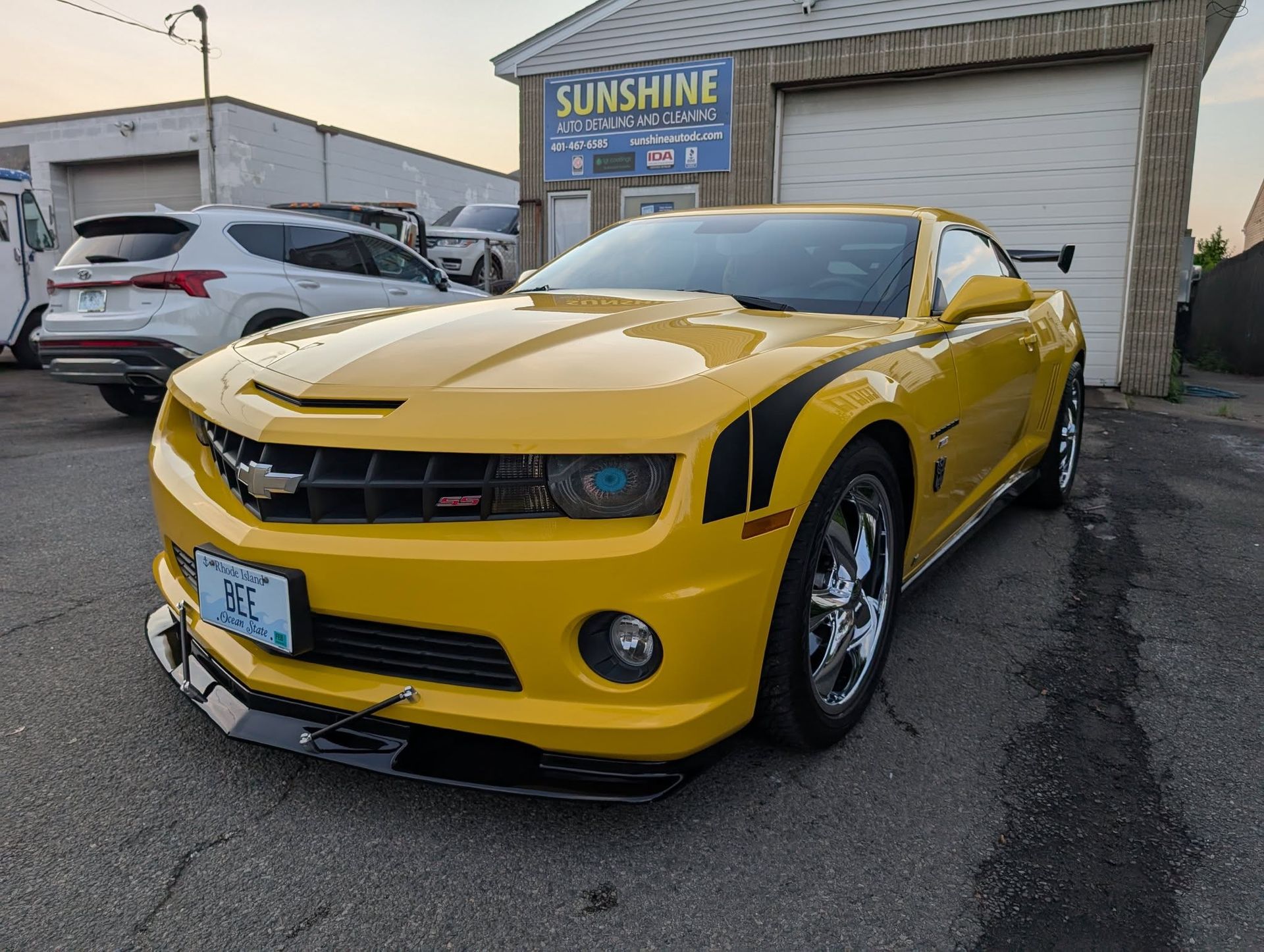 A yellow Chevrolet Camaro parked in front of a Sunshine building.