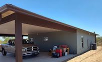 A truck is parked under a carport in front of a house.