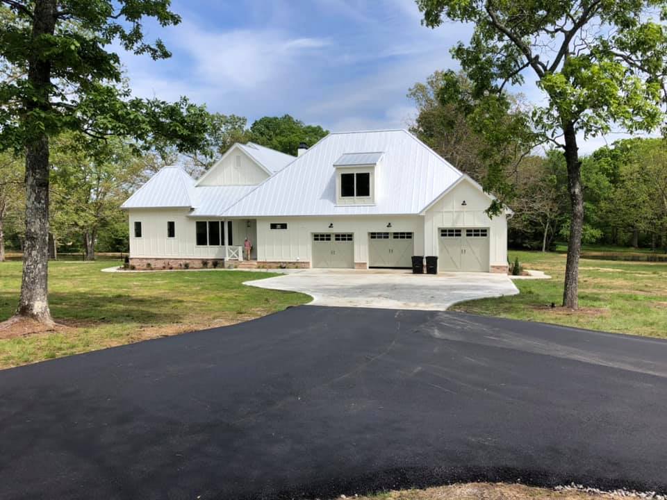 A white house with a white roof and a black driveway