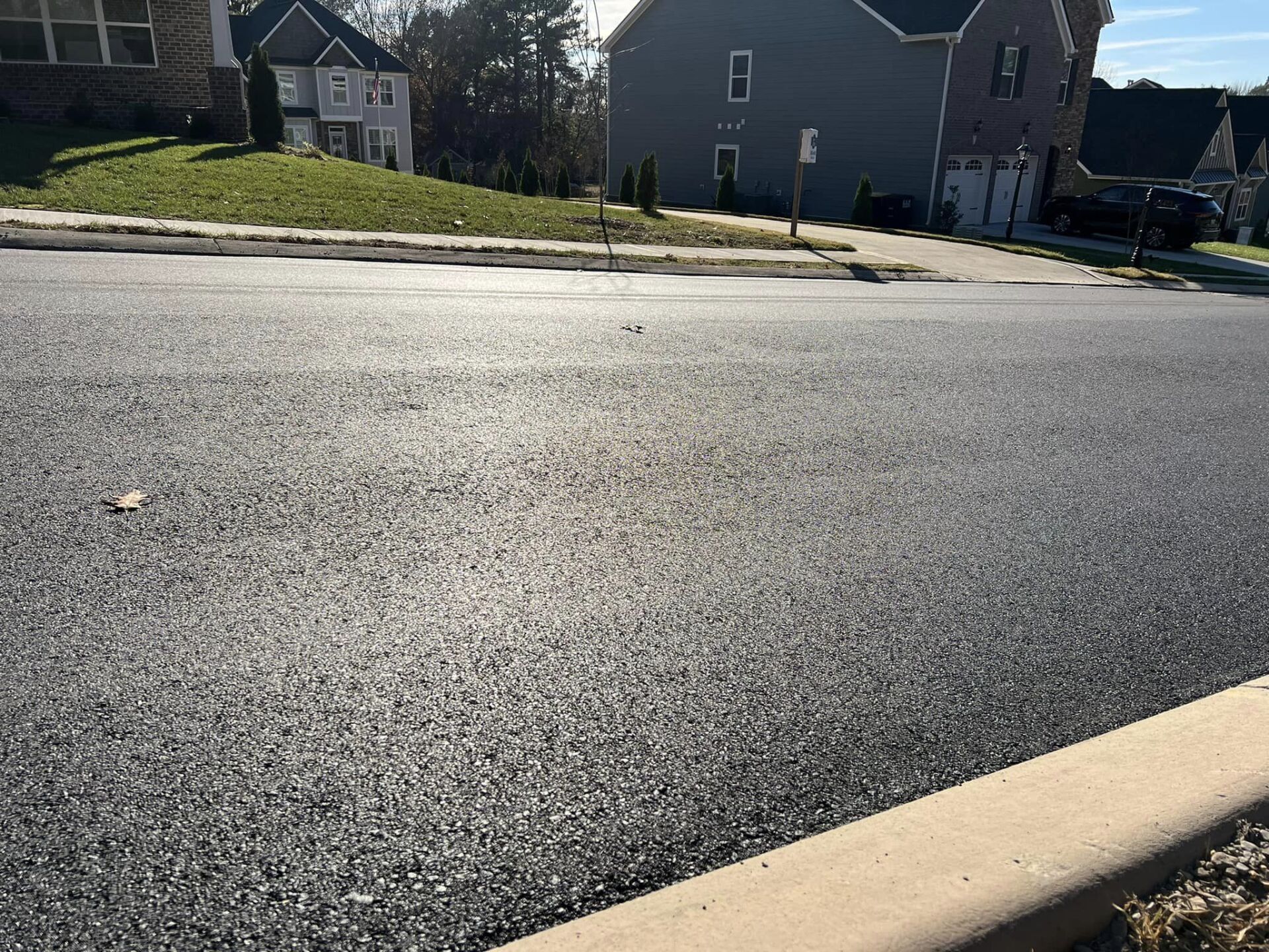 A road with a curb and a house in the background