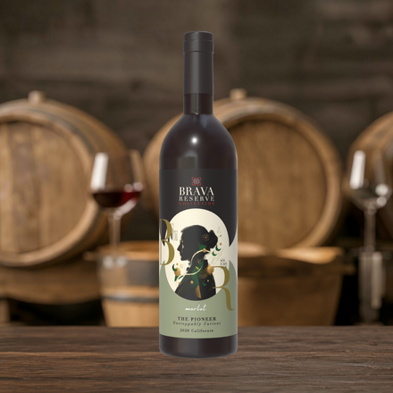 Bottle of red wine labeled “Bramasole” on a wooden table, with wine glasses and barrels in the background