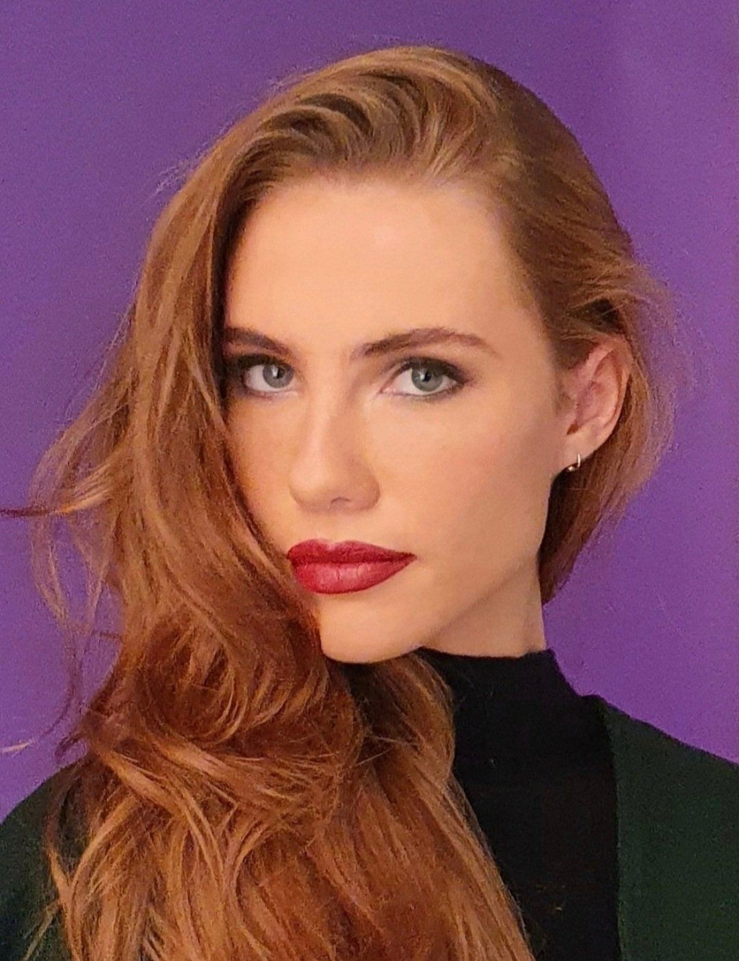 Purple background with ginger model wearing subtle eyes and bright red lips