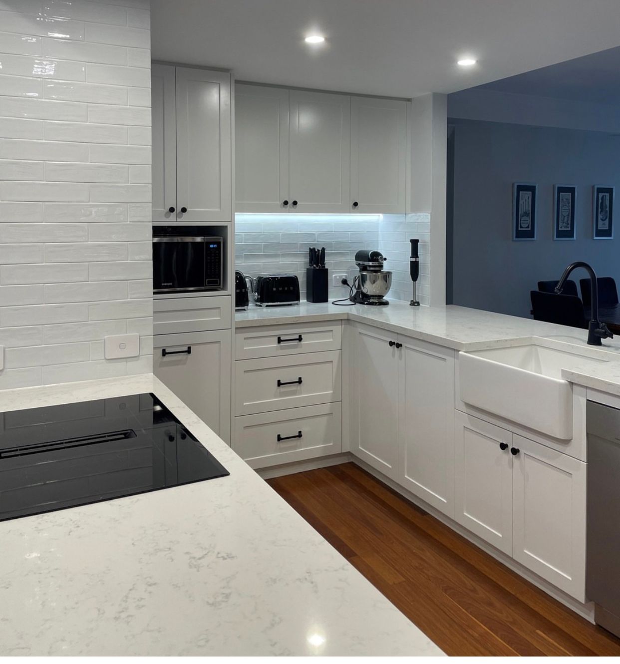 White kitchen with countertops, cabinets, and appliances. Includes a stove, sink, and microwave.