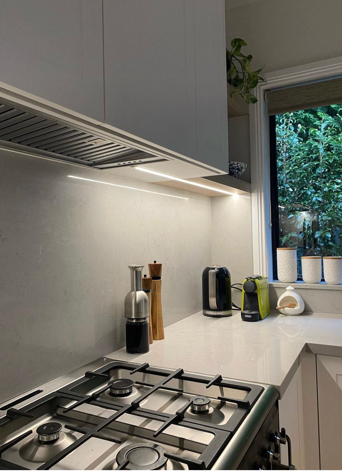 Kitchen with stove, countertop, cabinets, and a window overlooking greenery.