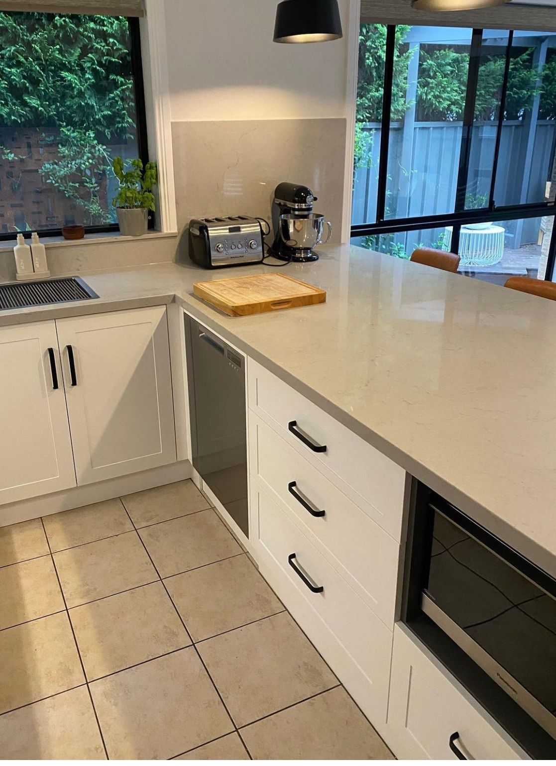 Modern kitchen with white cabinets, countertop, appliances, and a window.