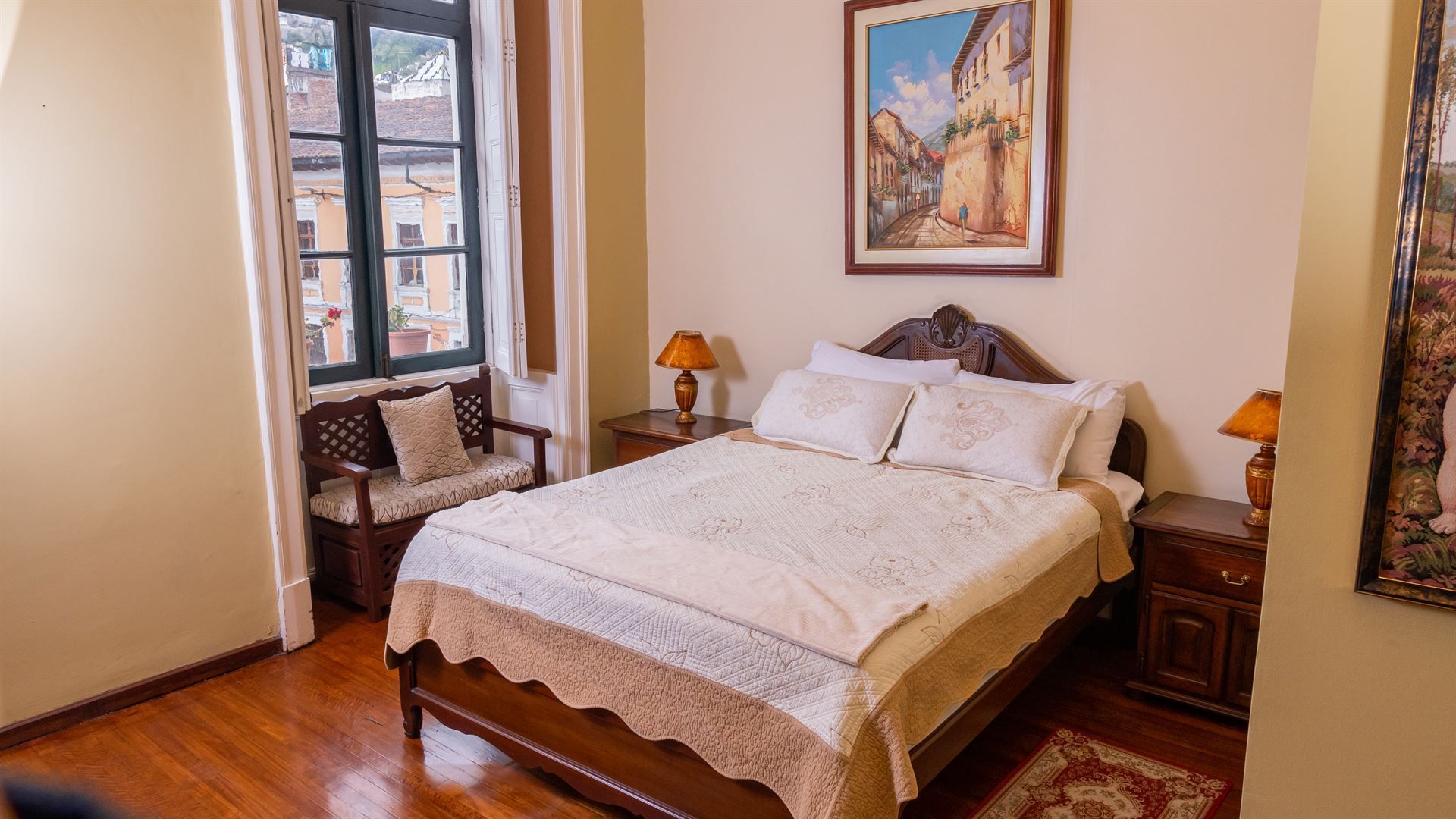 A bedroom with a bed , two nightstands , a chair and a painting on the wall.