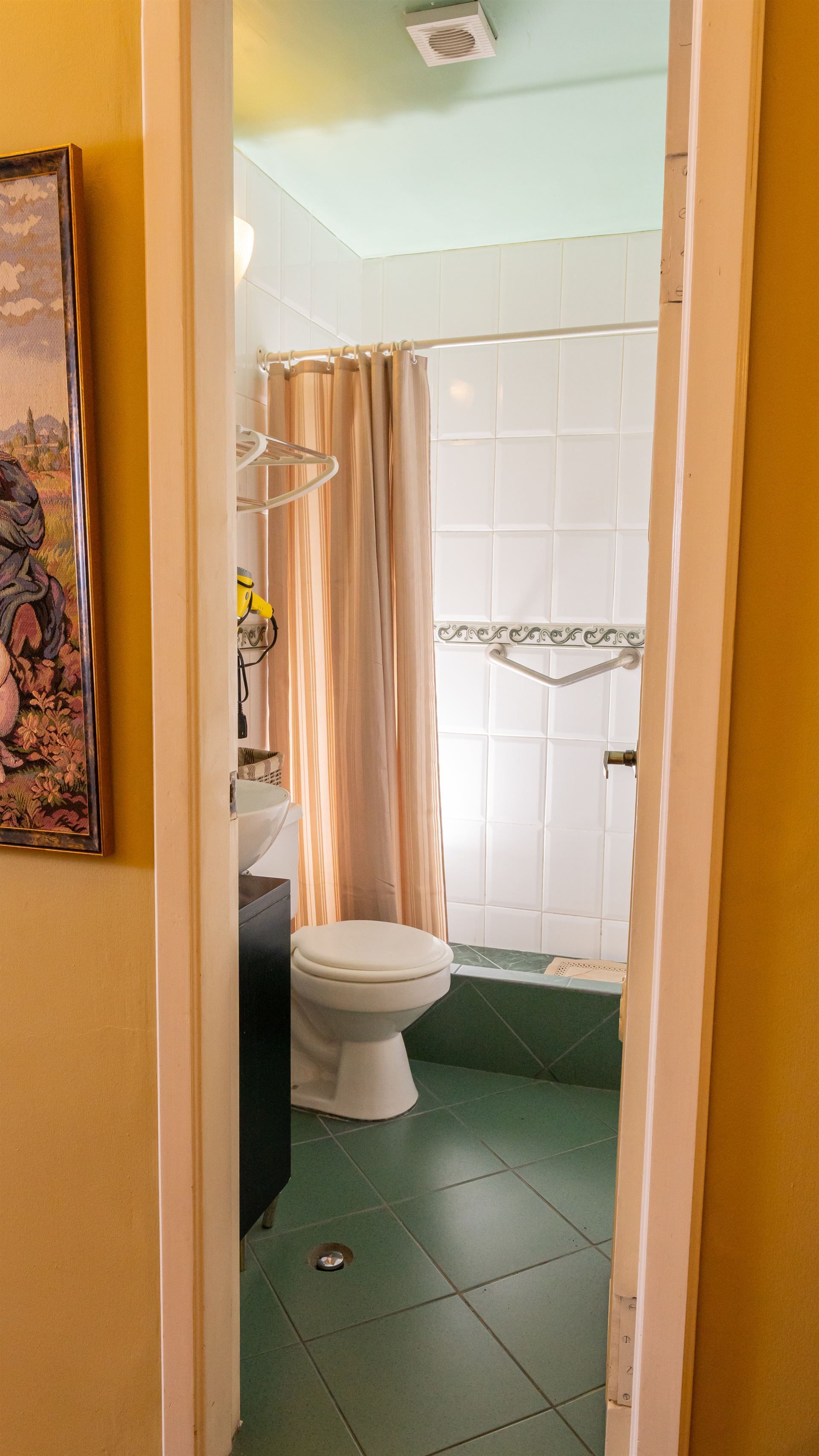 A bathroom with a toilet , sink and shower.