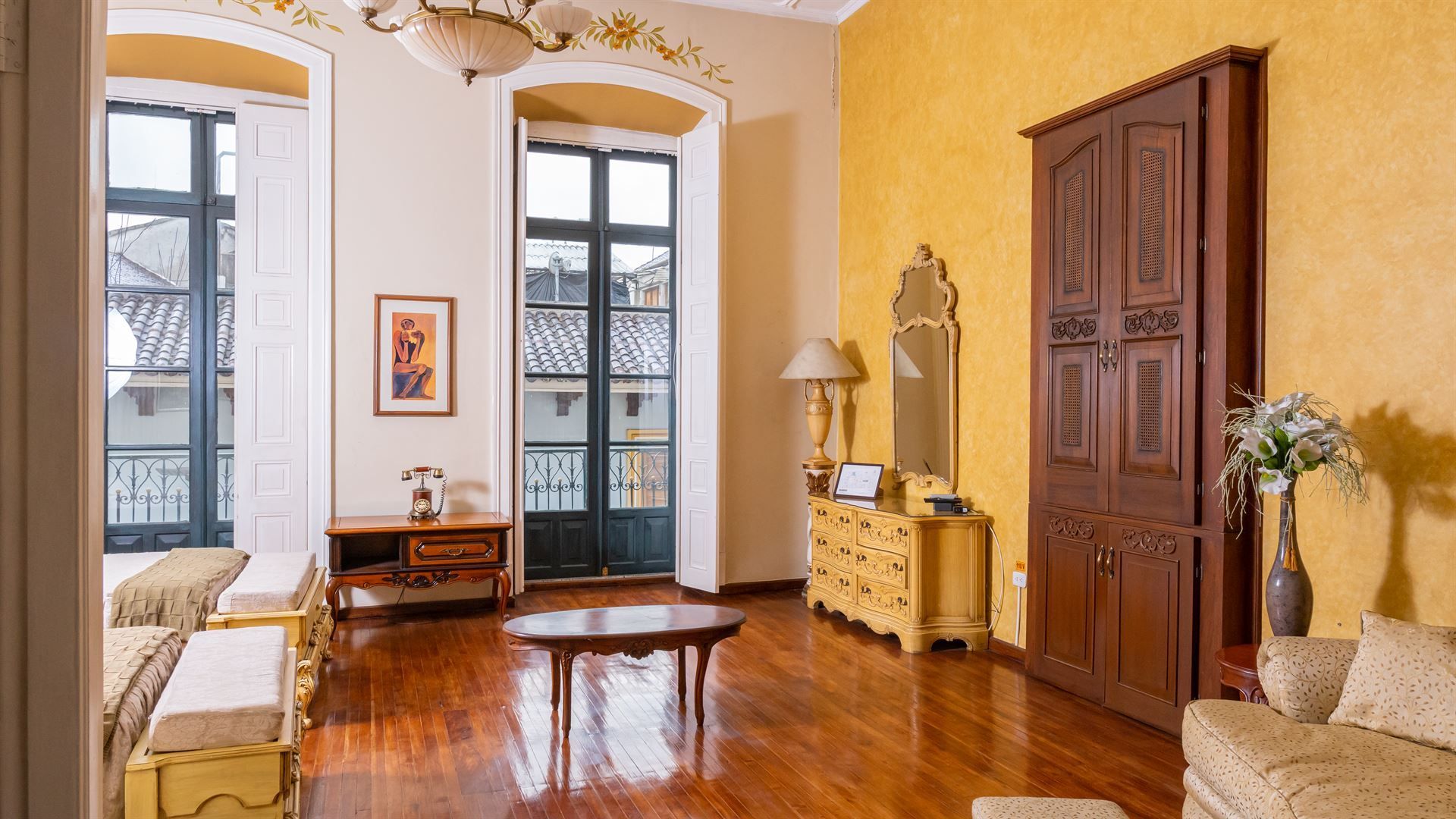 A living room with hardwood floors , a couch , a table and a mirror.