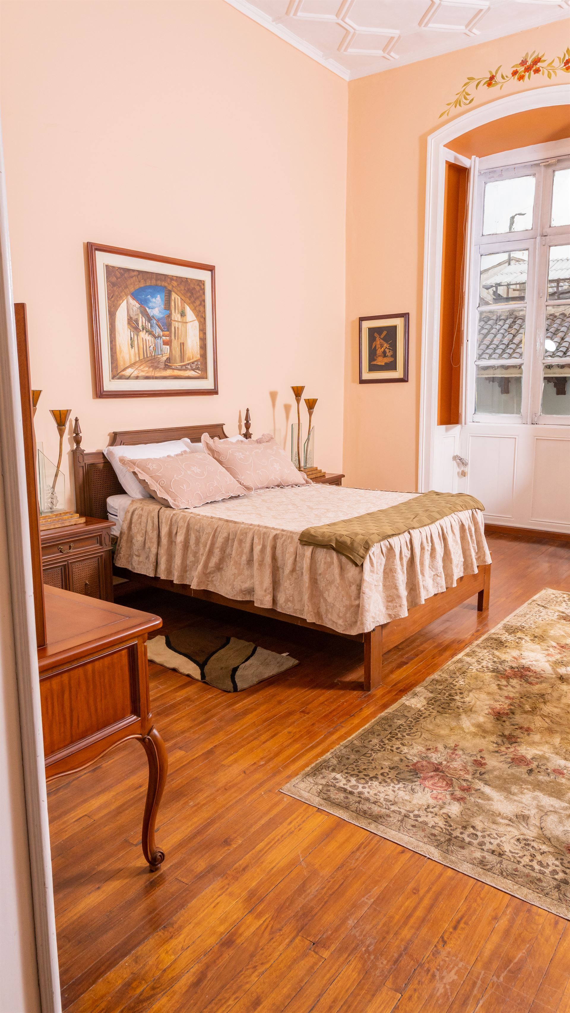 A bedroom with a bed , desk , nightstand and rug.