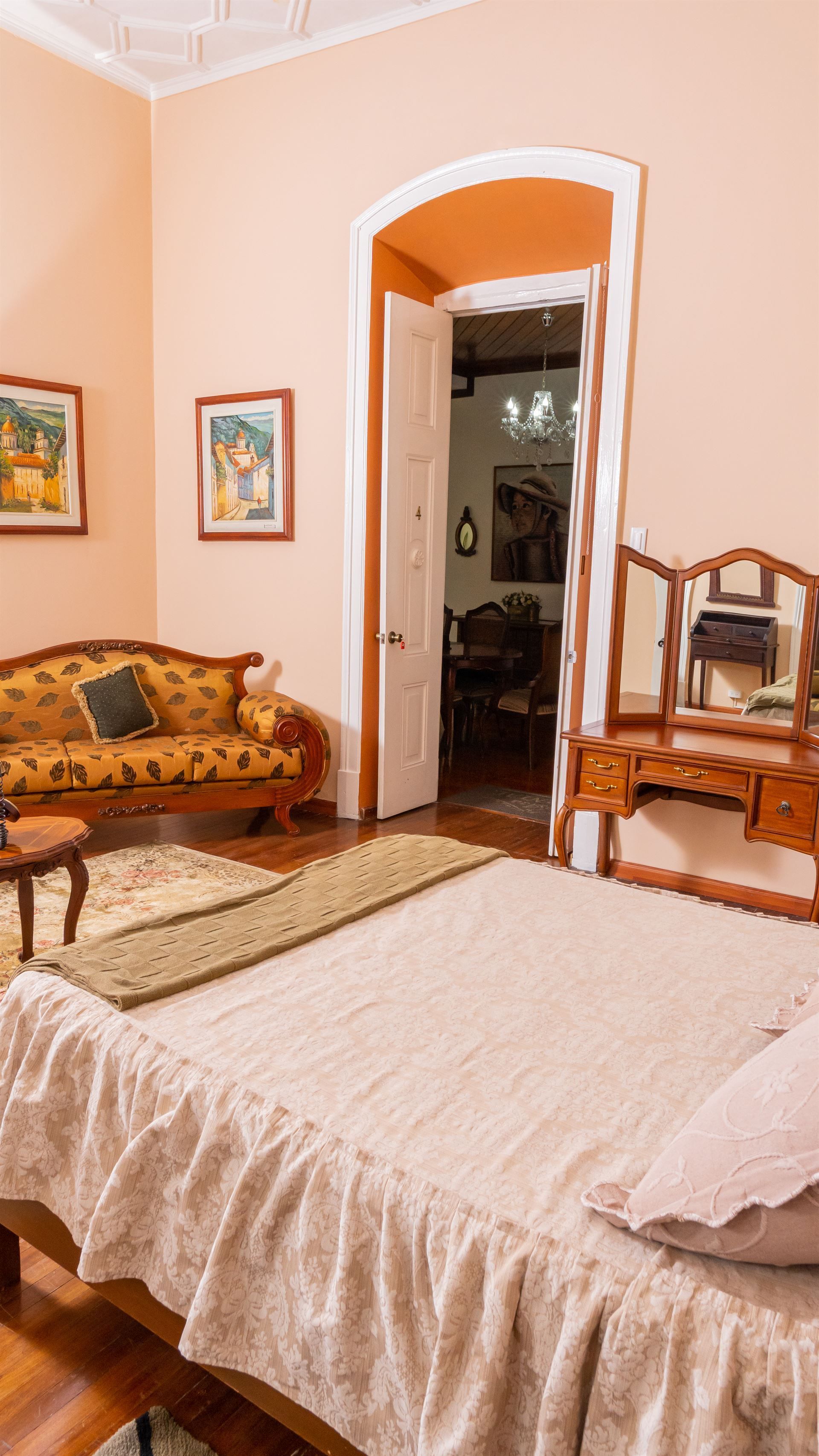 A bedroom with a bed , couch , dresser and mirror.