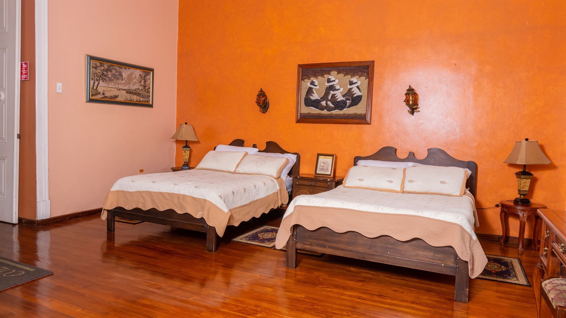 There are two beds in a room with orange walls.