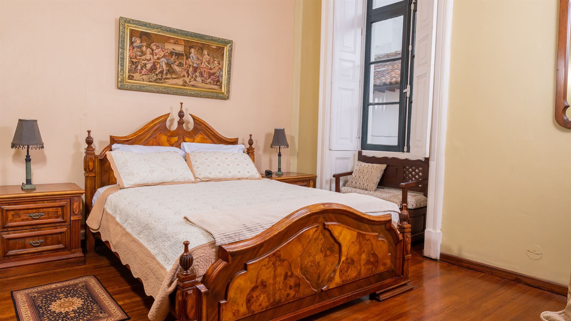 A bedroom with a bed , nightstands , lamps and a picture on the wall.