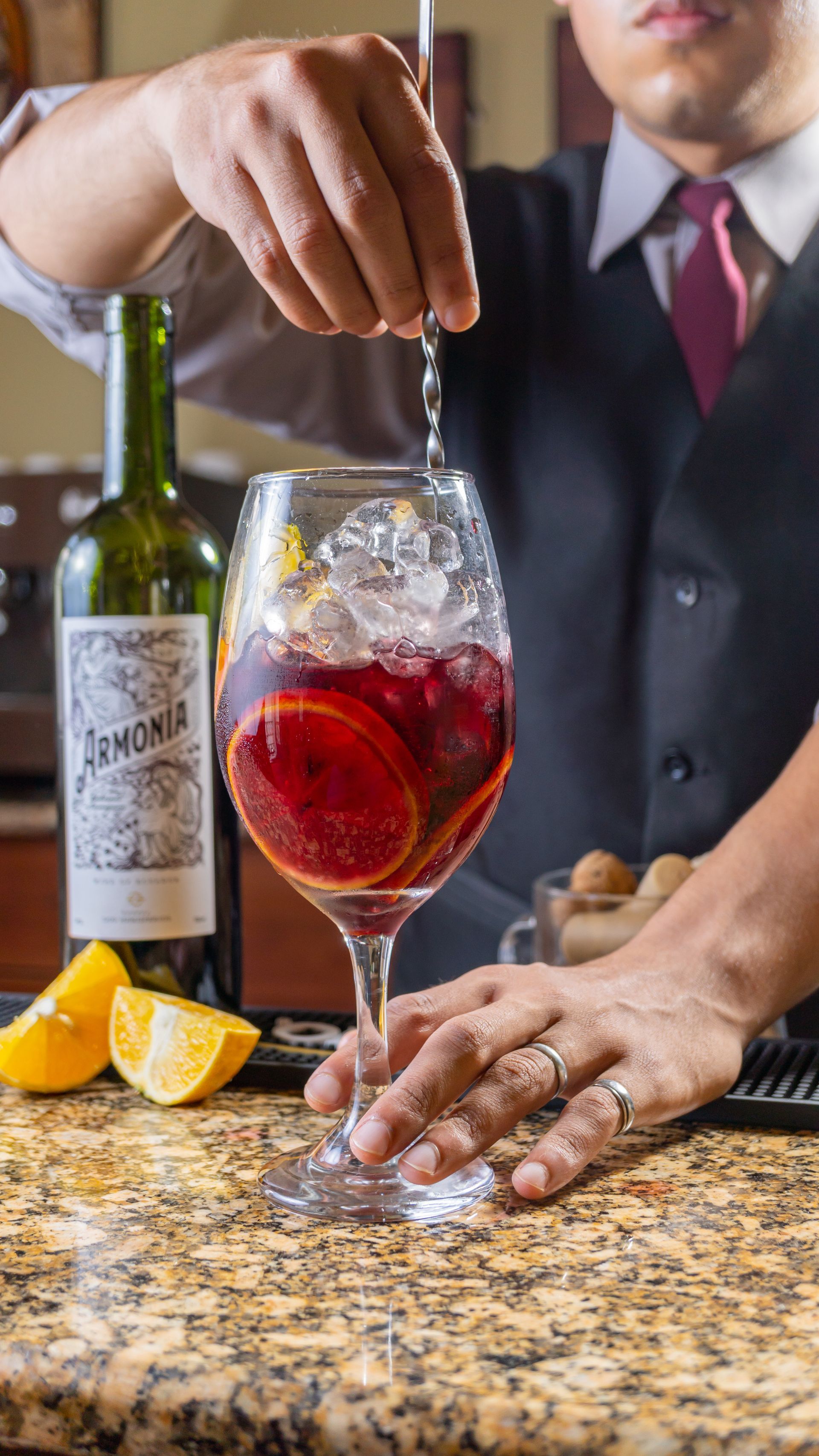 A bartender is pouring a drink into a glass on a counter.