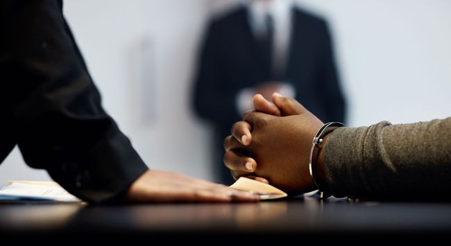 Hands clasped across a meeting table with two blurred people in the background
