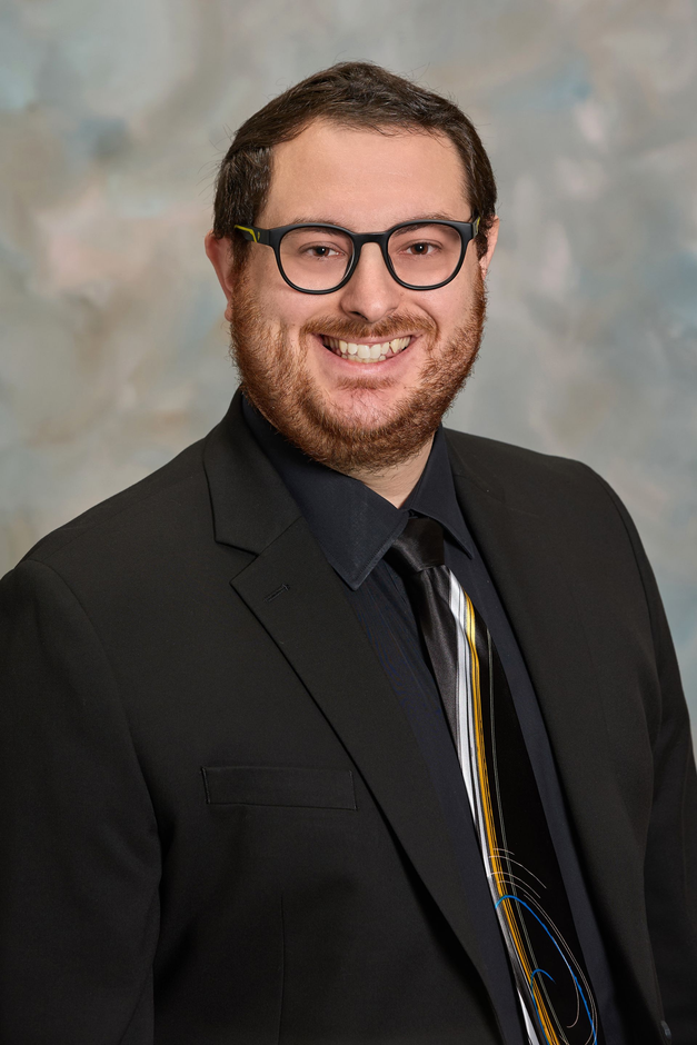 A man in a suit and tie is smiling for the camera