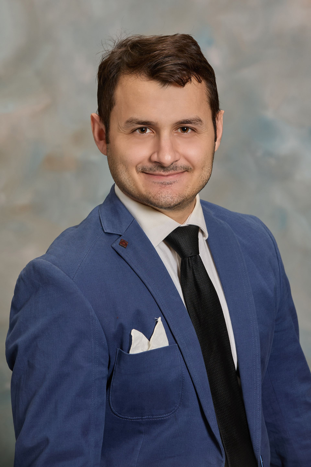 A man in a suit and tie is smiling for the camera