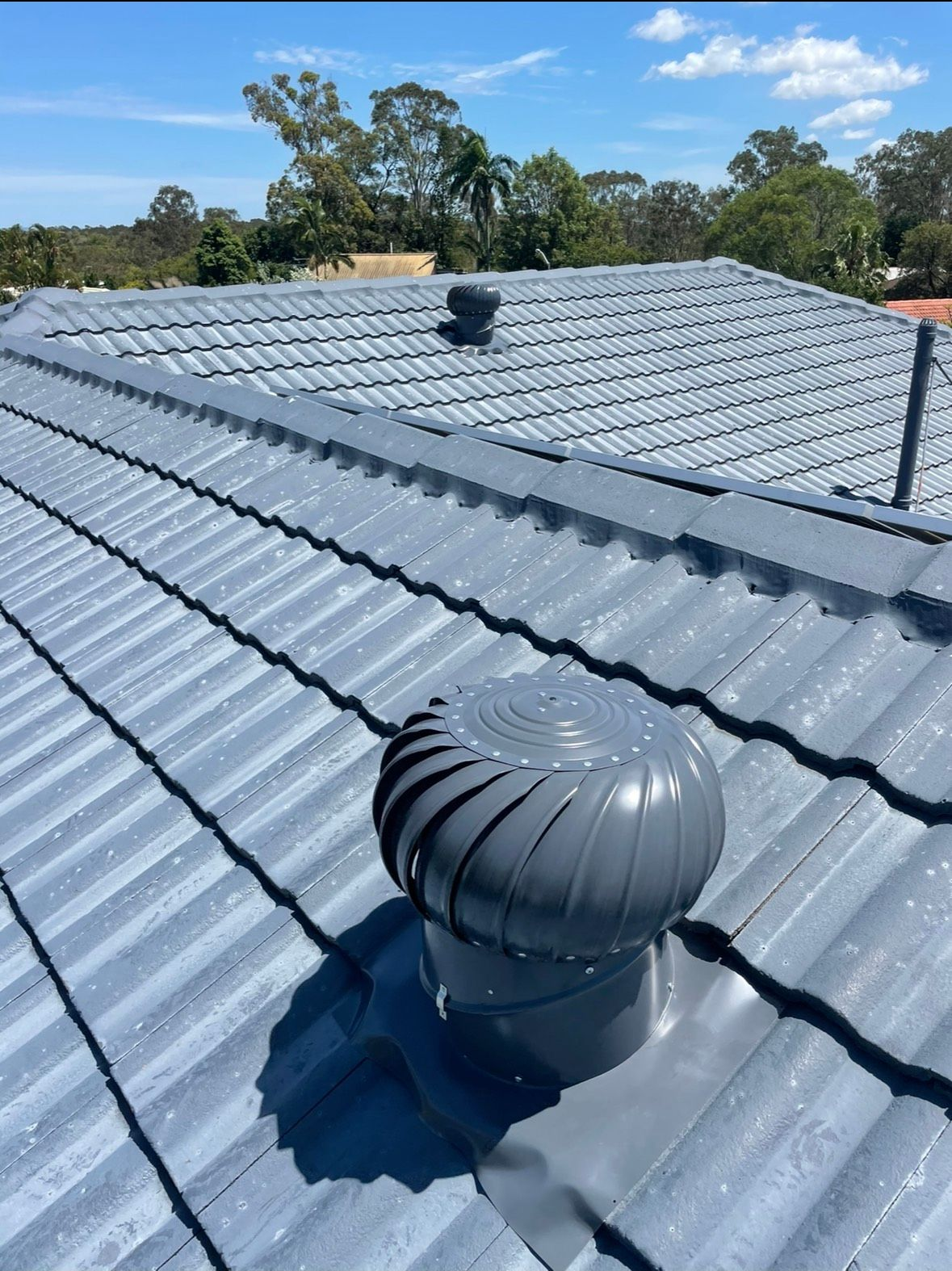 Spinning metal roof vent against a bright blue sky.