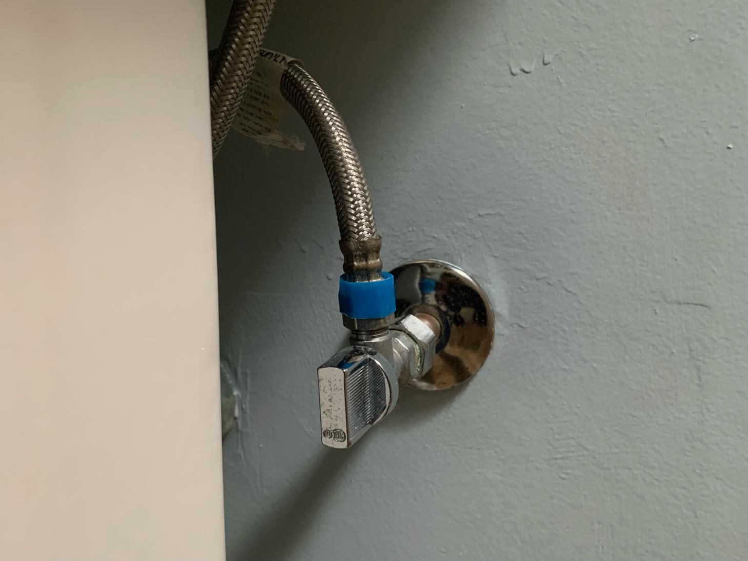 A close up of a valve on a wall next to a sink.