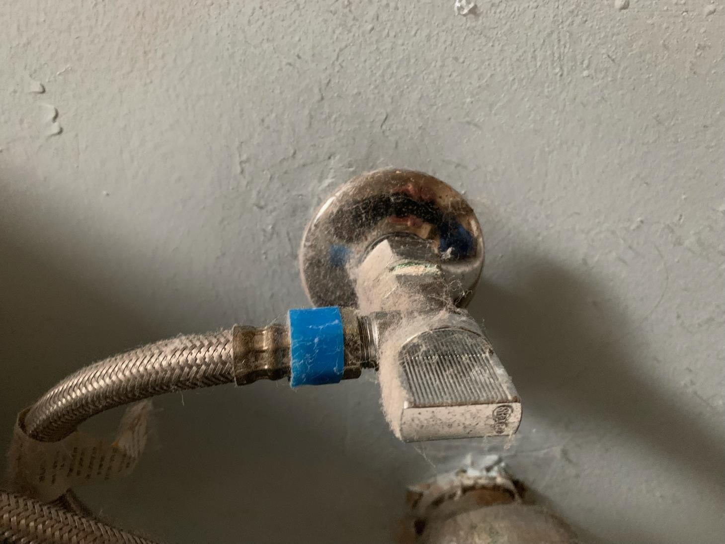 A close up of a faucet on a white wall.