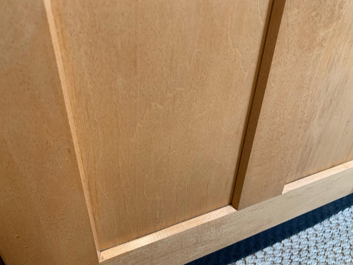 A close up of a wooden door with a carpet in the background.