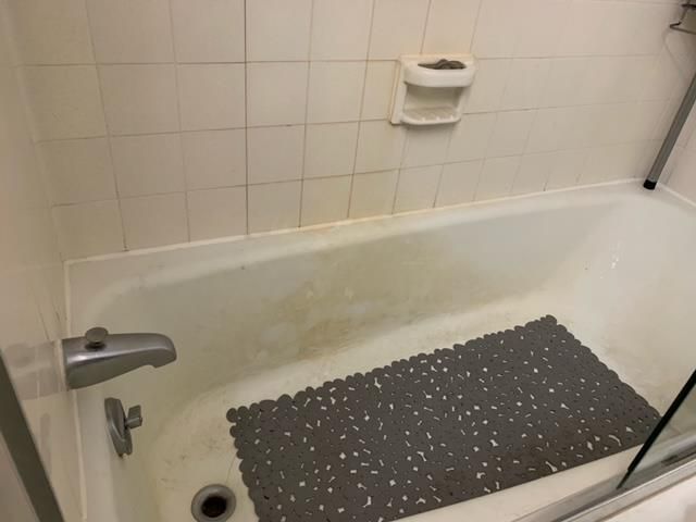 A bathtub with a gray mat on the floor